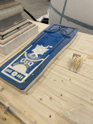 Blaue und cremefarbene Silikonform mit ägyptischen Motiven liegt auf einem Holztisch neben weiteren Gussformen.