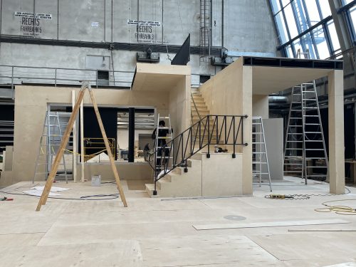 Bau einer modernen Innenkonstruktion mit Holzplatten, Leitern und Werkzeugen in einer großen Halle.
