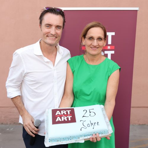 Ein Mann und eine Frau halten gemeinsam eine Torte mit der Aufschrift „ART ART 25 Jahre“.